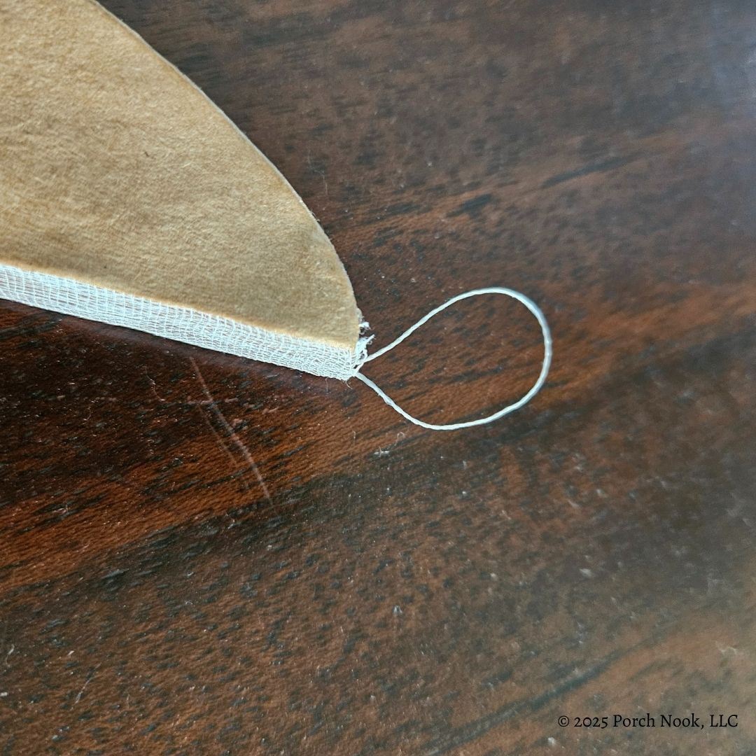 Close-up of a brown fabric corner with a string hanger on a wooden surface.