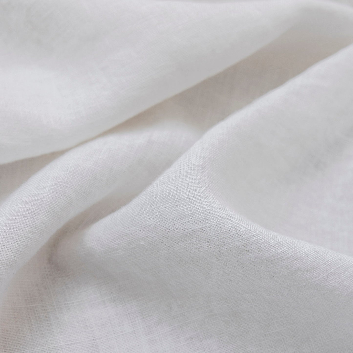 A close-up of draped white fabric with a soft, slightly textured weave and gentle folds.