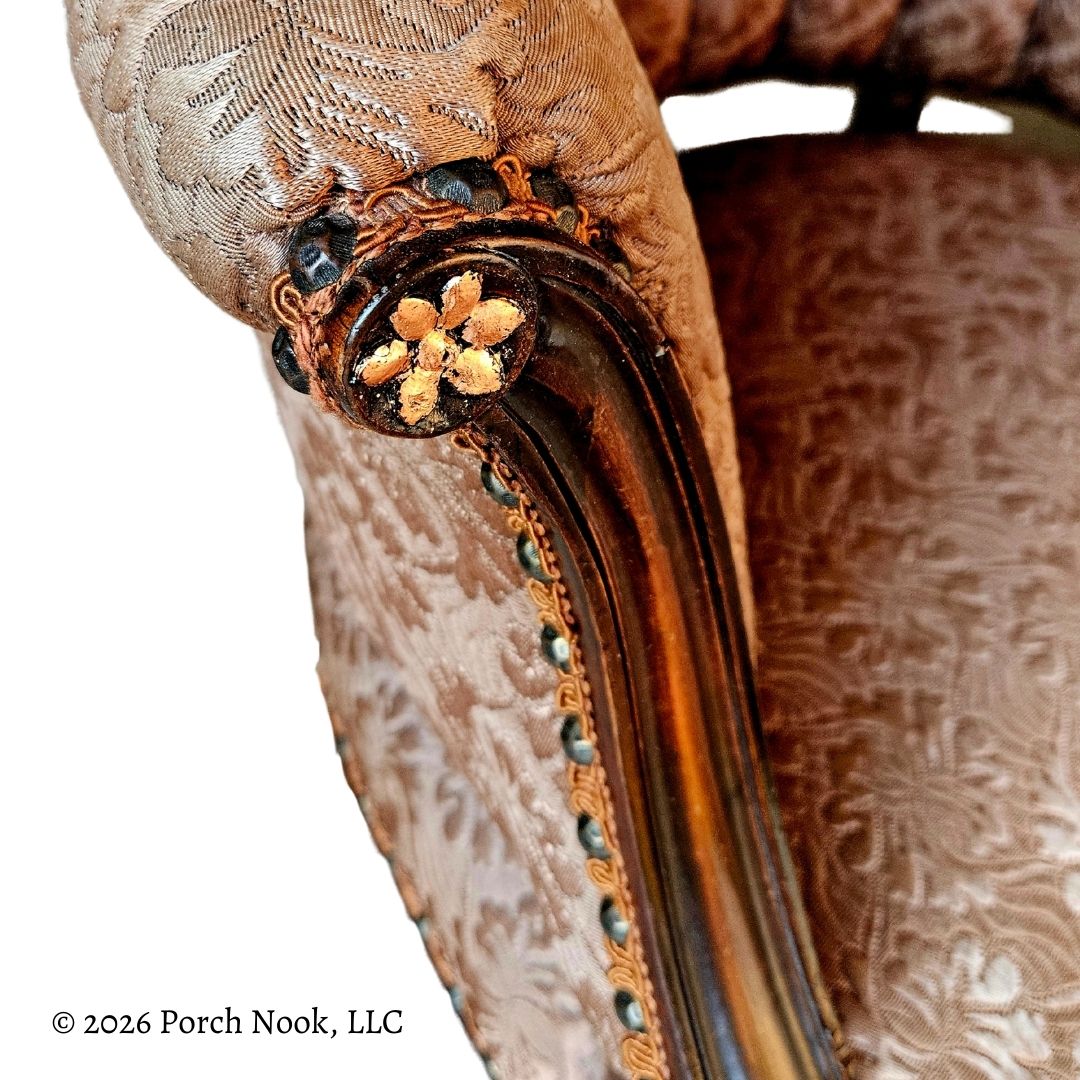 Close-up of an ornate chair arm with intricate detailing on a white background.