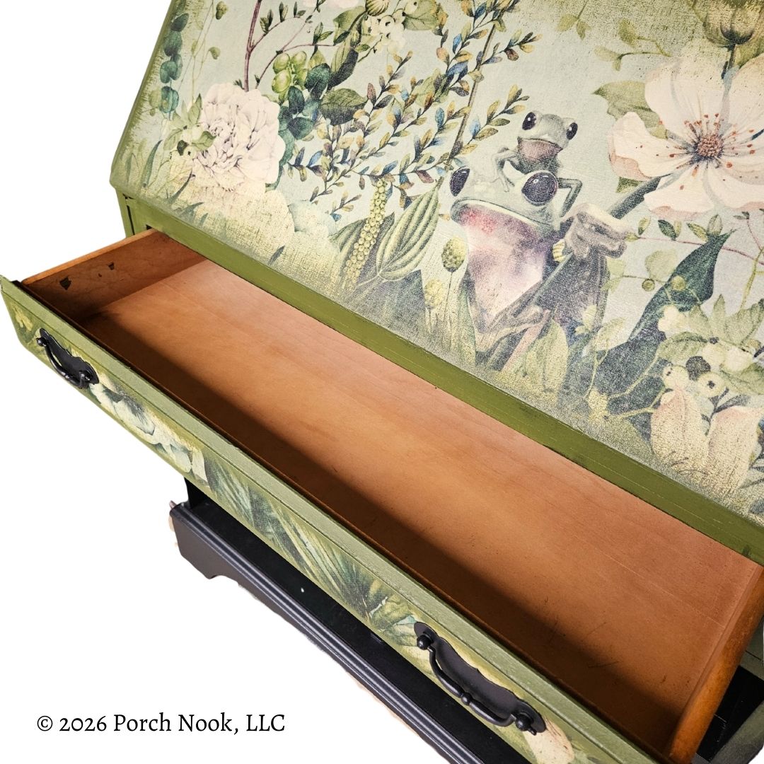 Close view of top drawer opened on vintage secretary desk showing botanical frog decoupage on drawer face and wood drawer interior