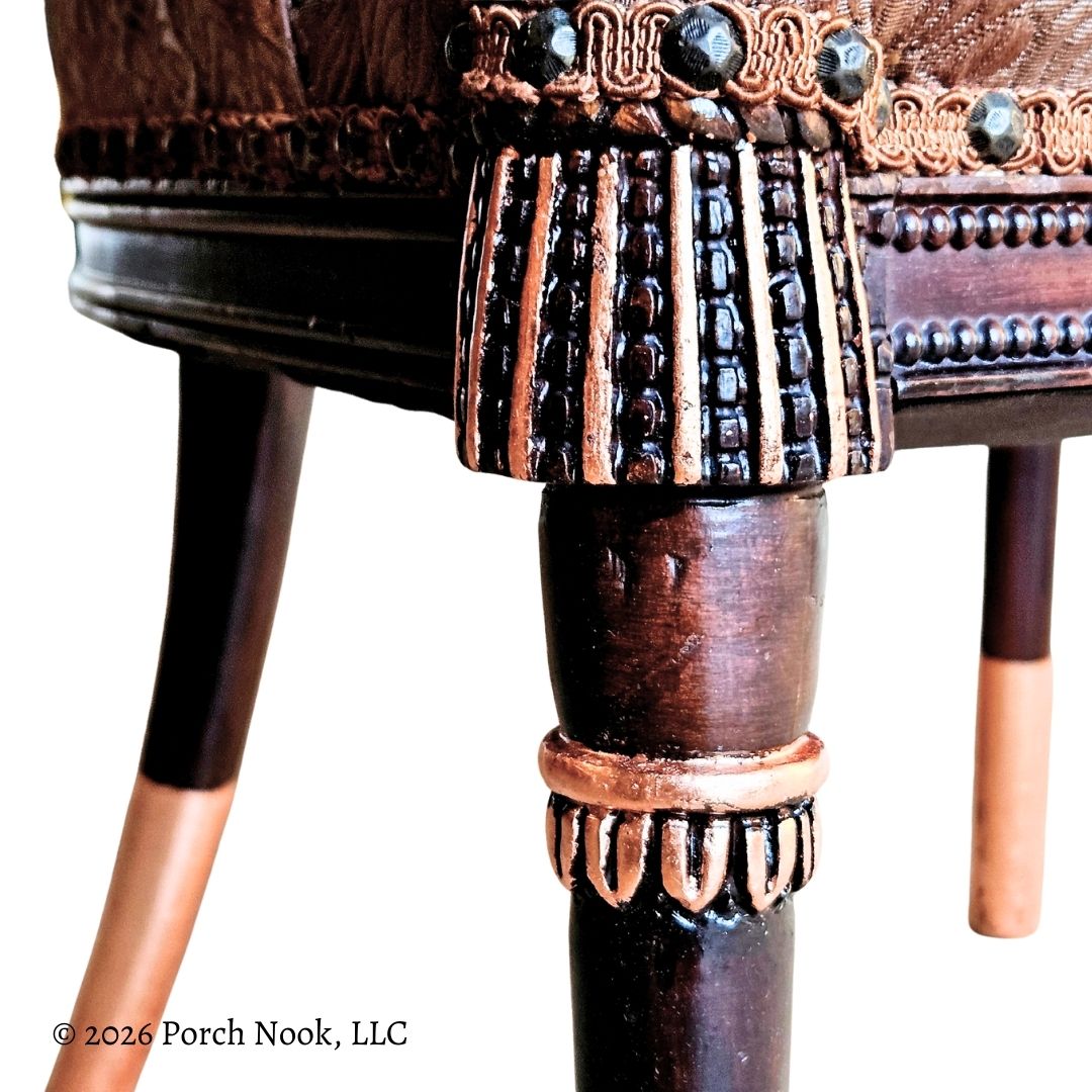 Close-up of a decorative wooden chair leg with intricate carvings and rose gold accents.