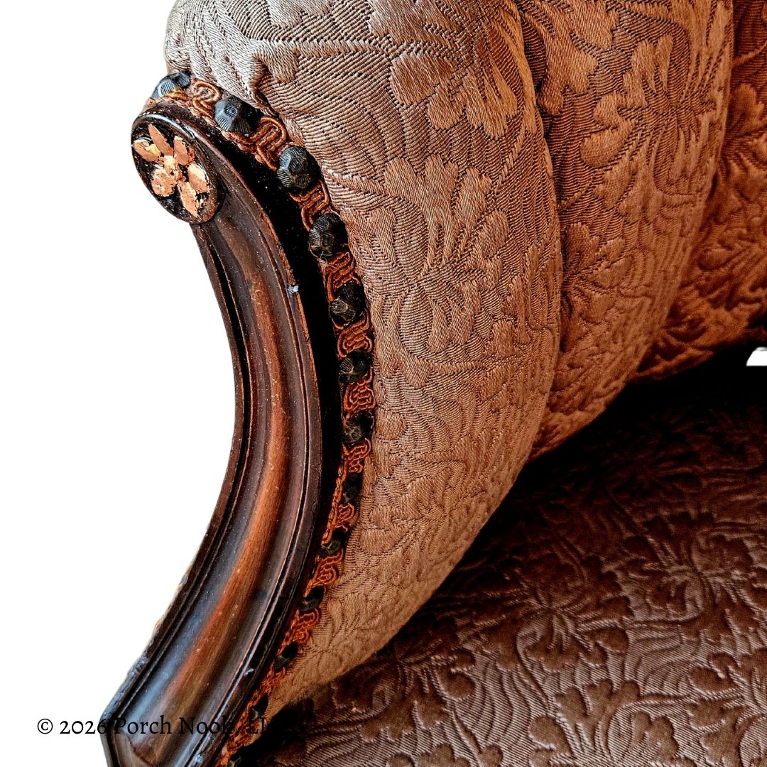 Close-up of a brown embroidered fabric with intricate patterns and decorative elements.