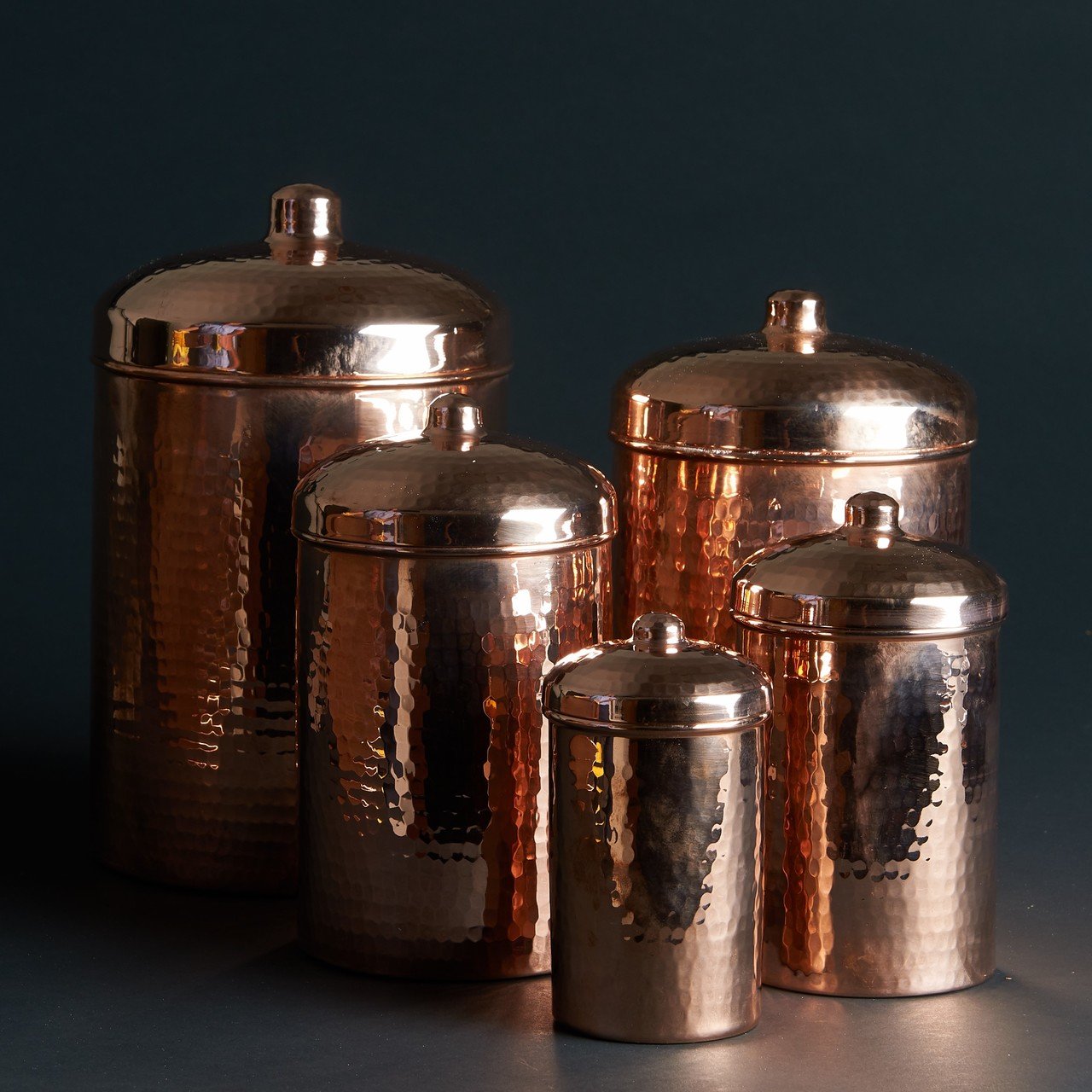Set of copper canisters with lids on a dark background