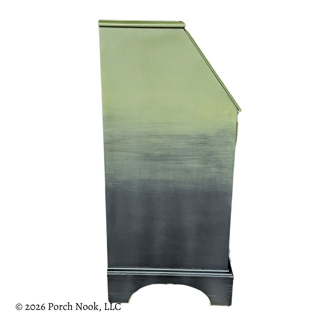 Side view of vintage secretary desk showing green to black ombre paint finish and classic curved base detail