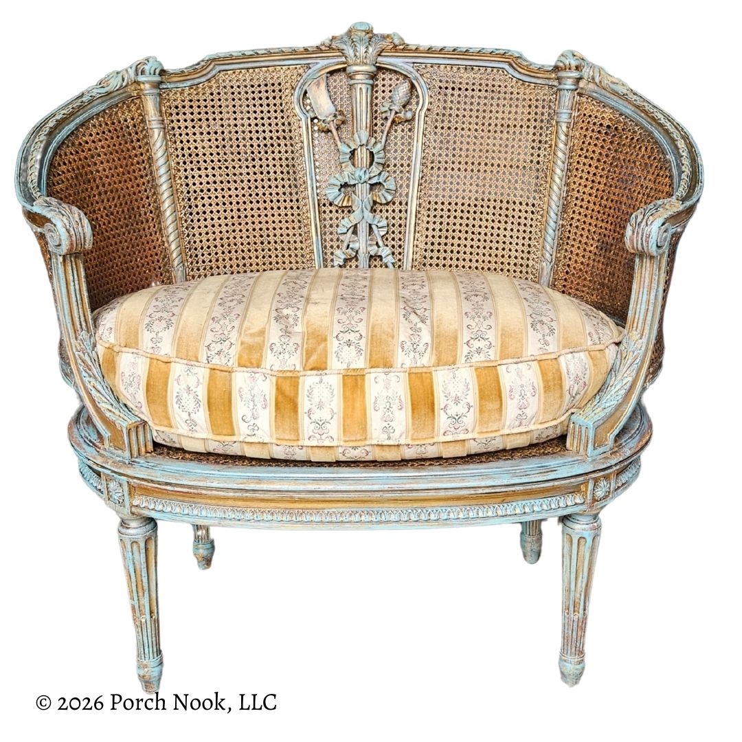 Decorative armchair with caned backrest and striped cushion on a white background