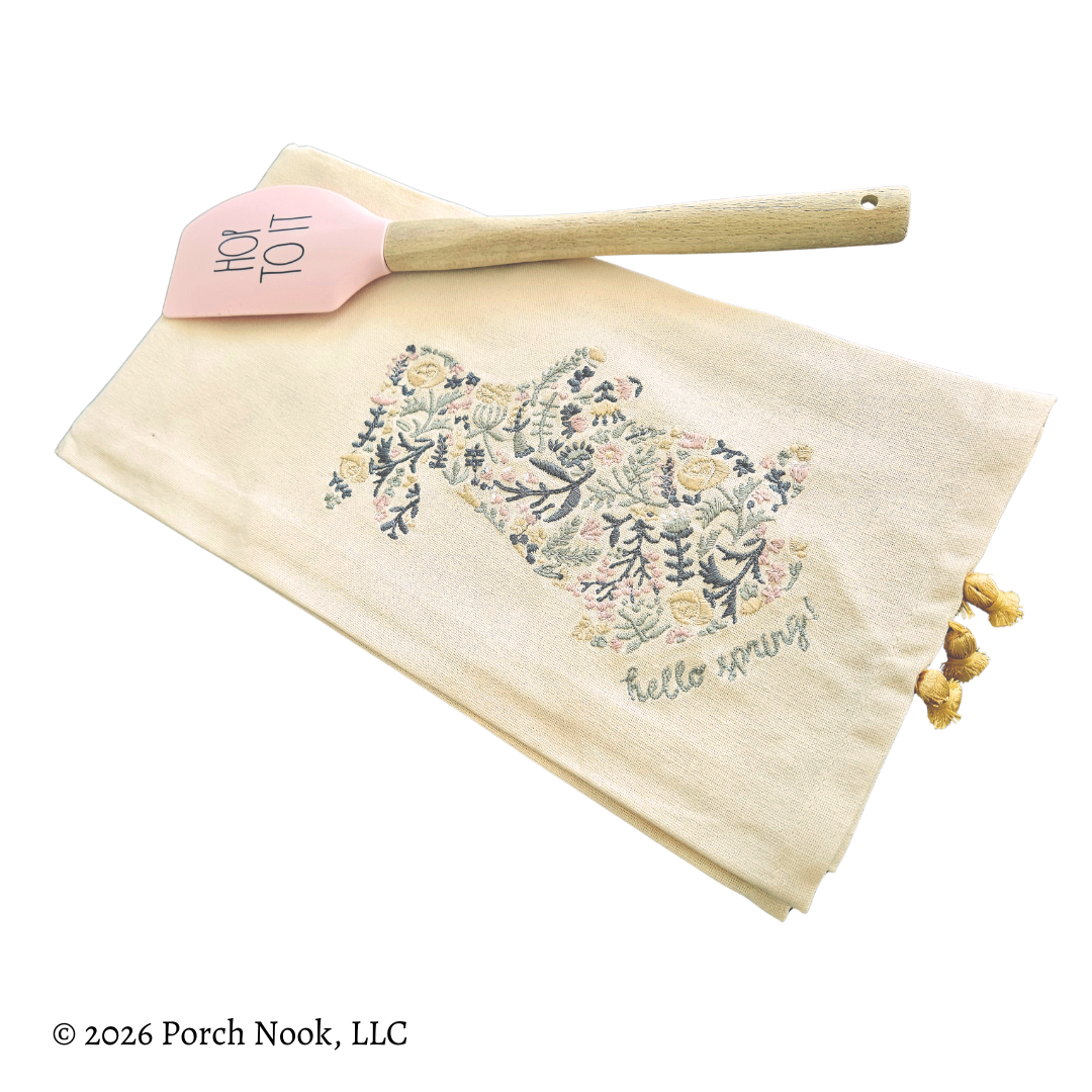 Floral towel with 'hello spring' text and pink spatula on a white background