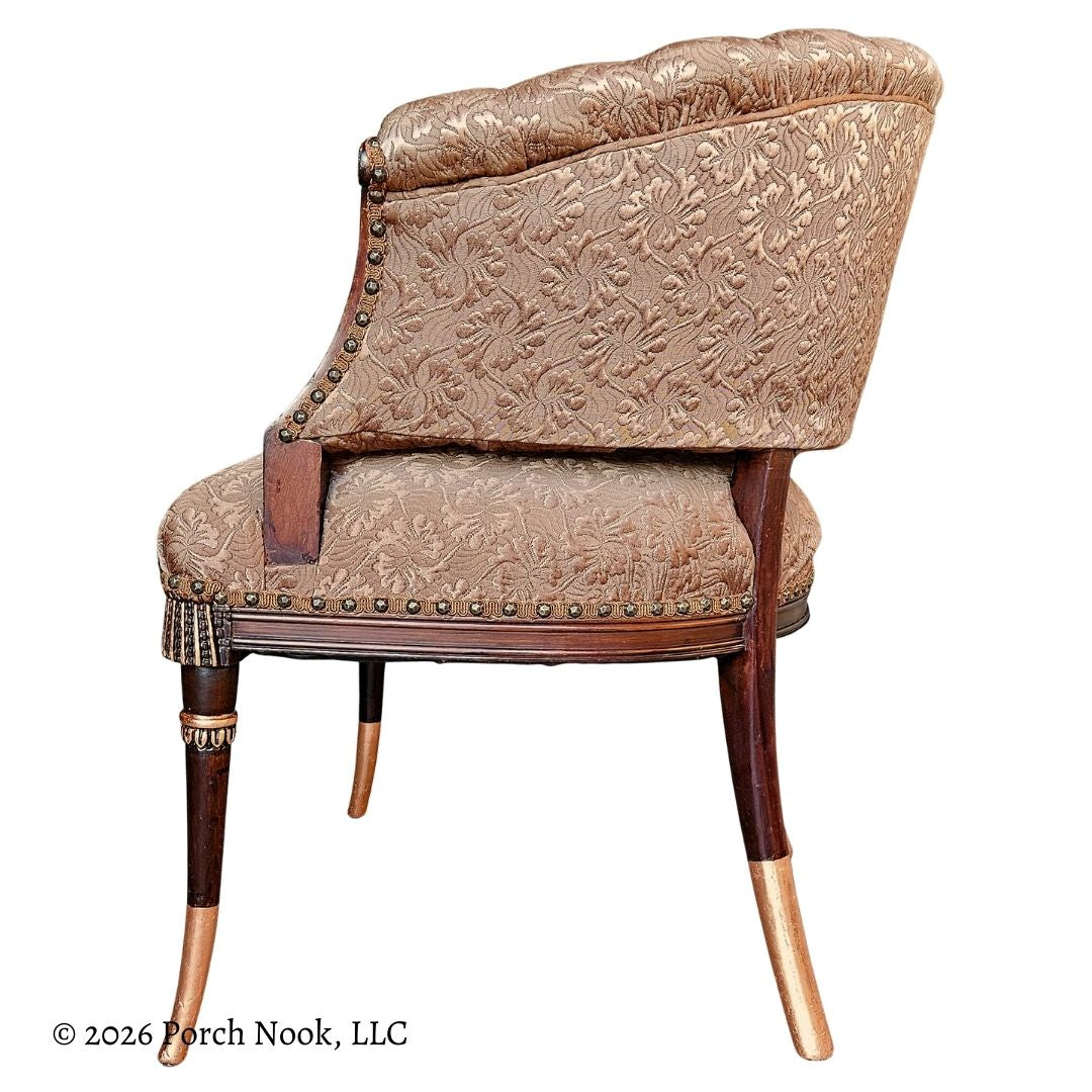 Decorative chair with floral pattern and wooden legs accented with metallic copper gilding on a white background