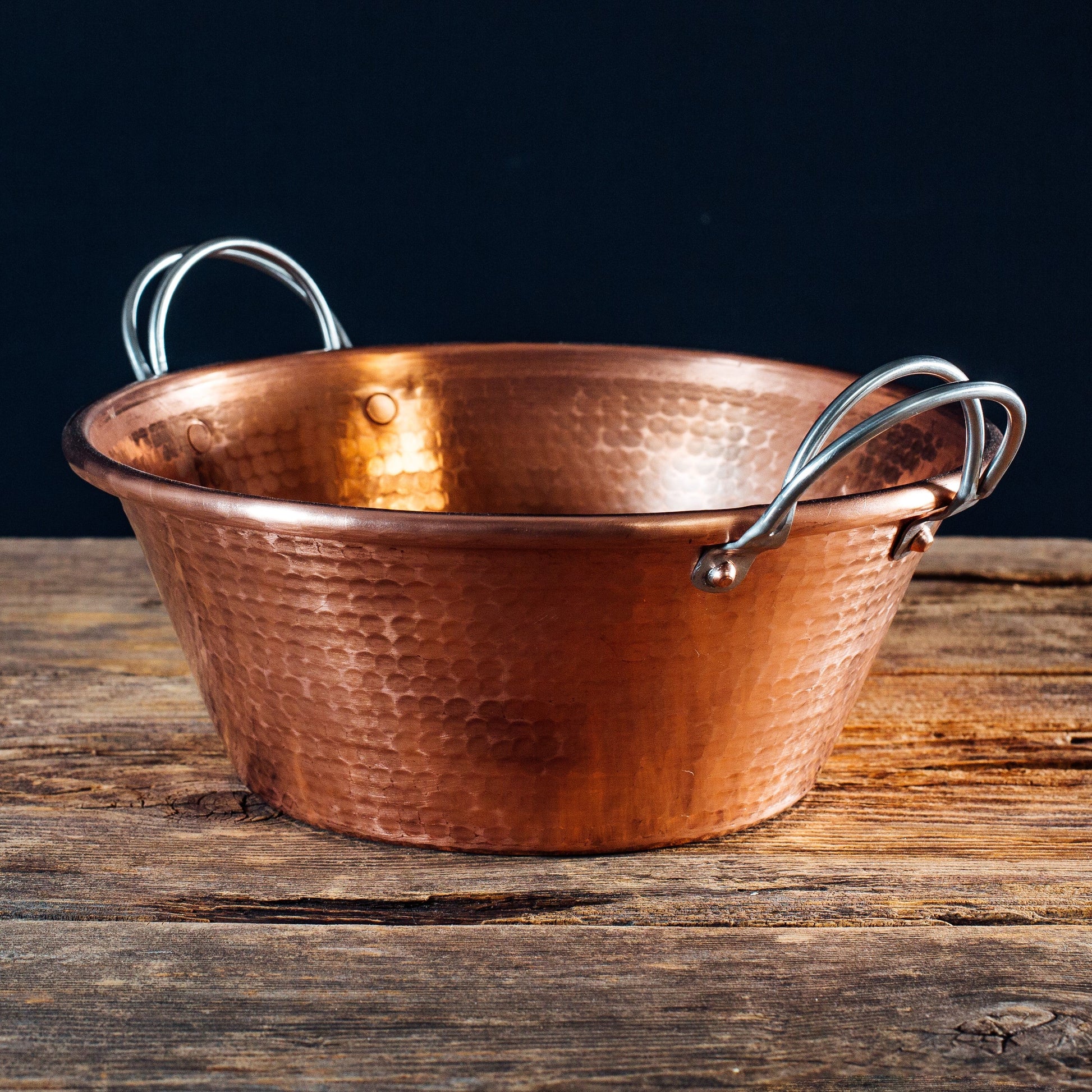 Copper pot with handles on a wooden surface