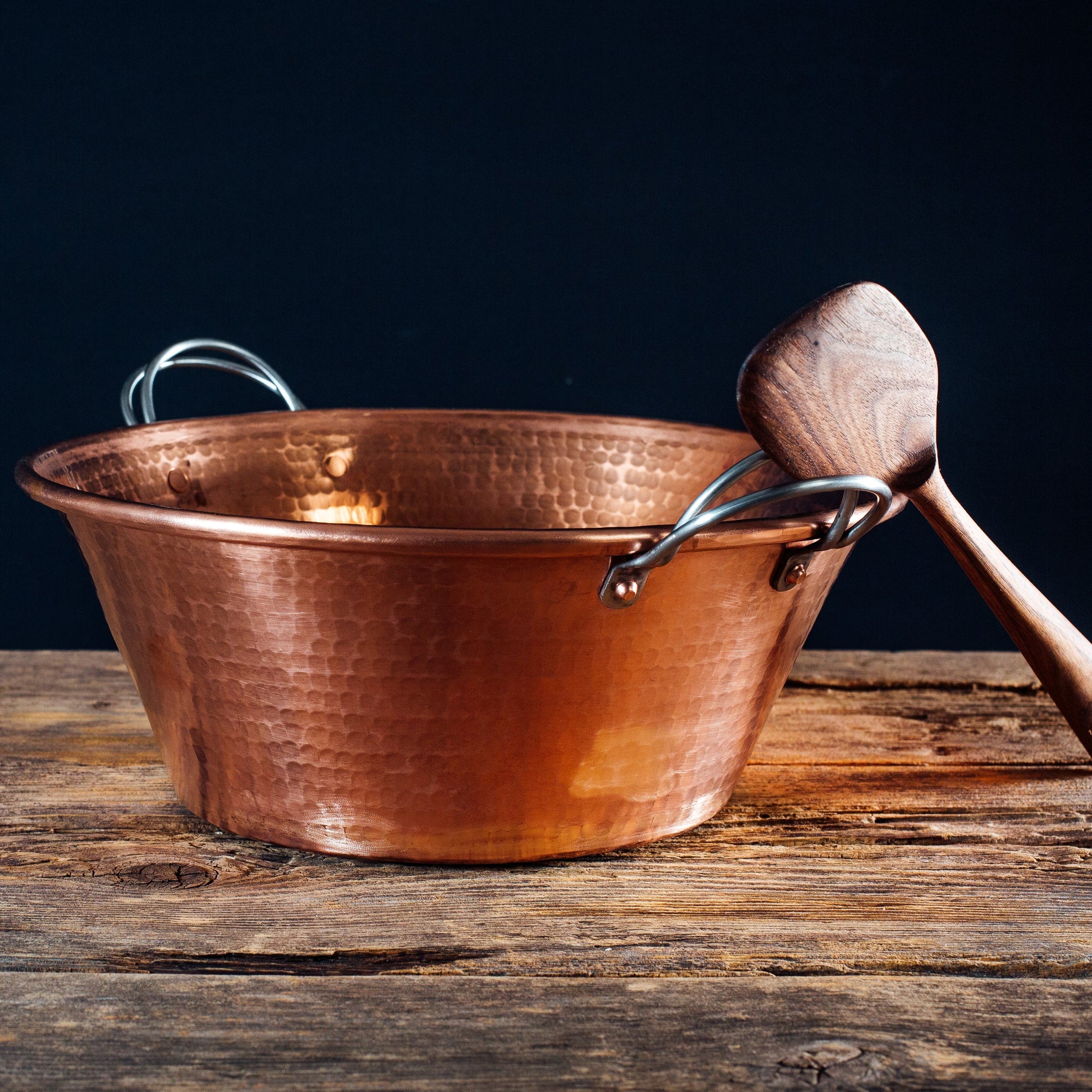 Copper bathtub with wooden spoon on a wooden surface