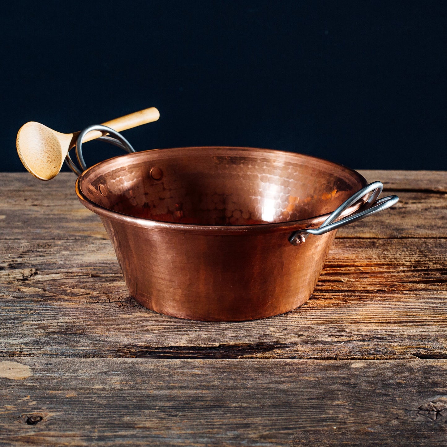 Copper pot with handles on a wooden surface