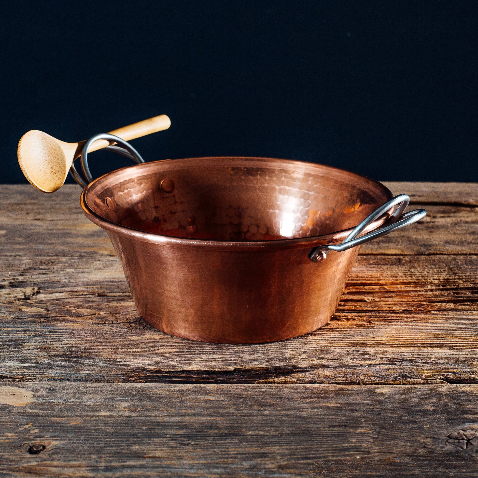 Copper pot with handles on a wooden surface