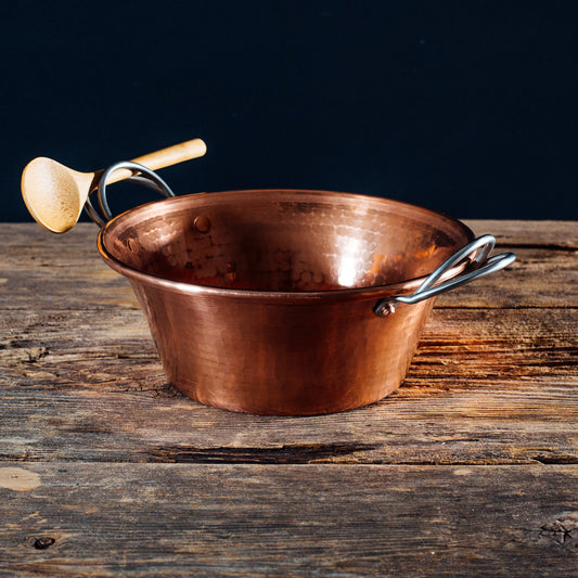Copper pot with handles on a wooden surface