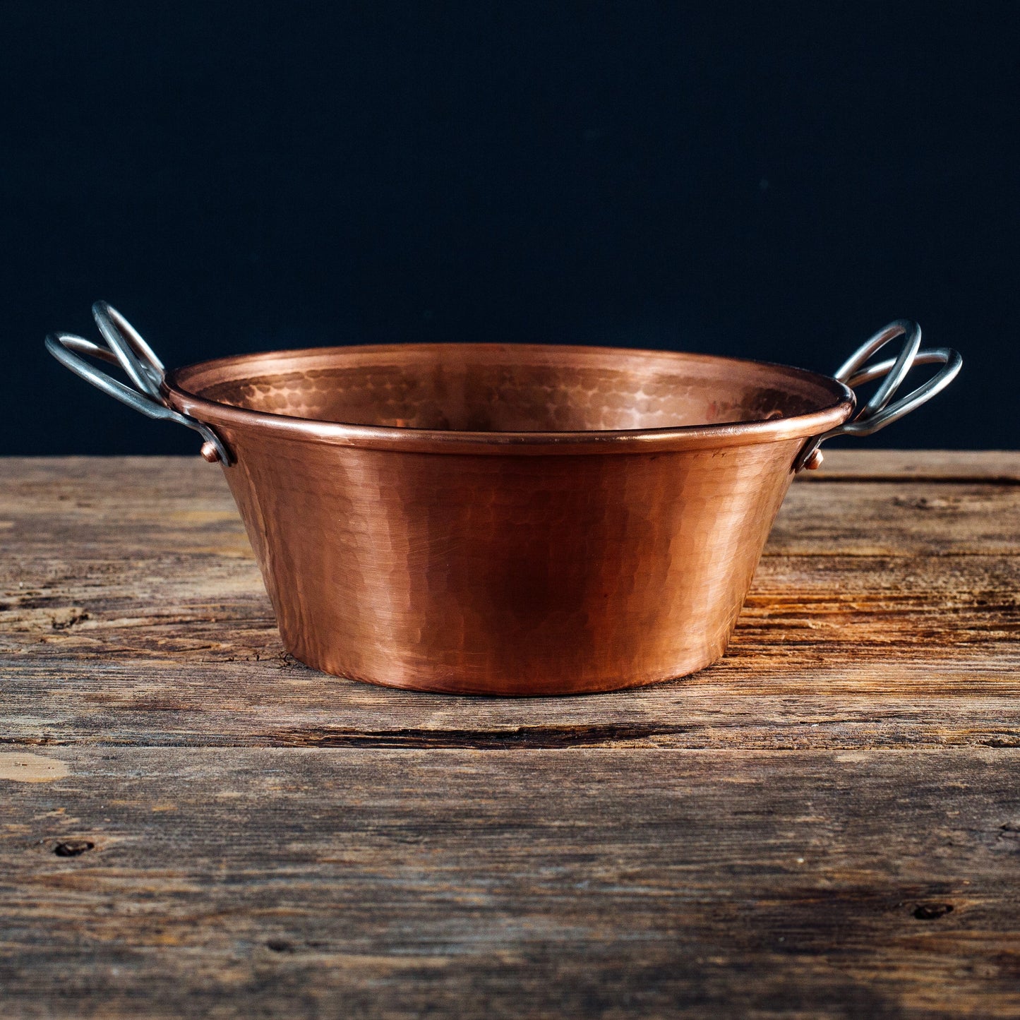 Copper pot with handles on a wooden surface