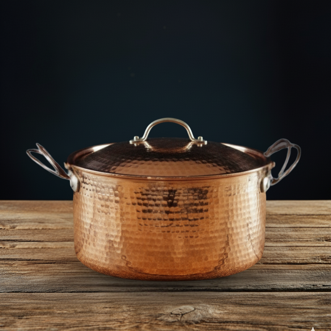 Copper Dutch Oven pot with lid on a wooden surface against a dark background