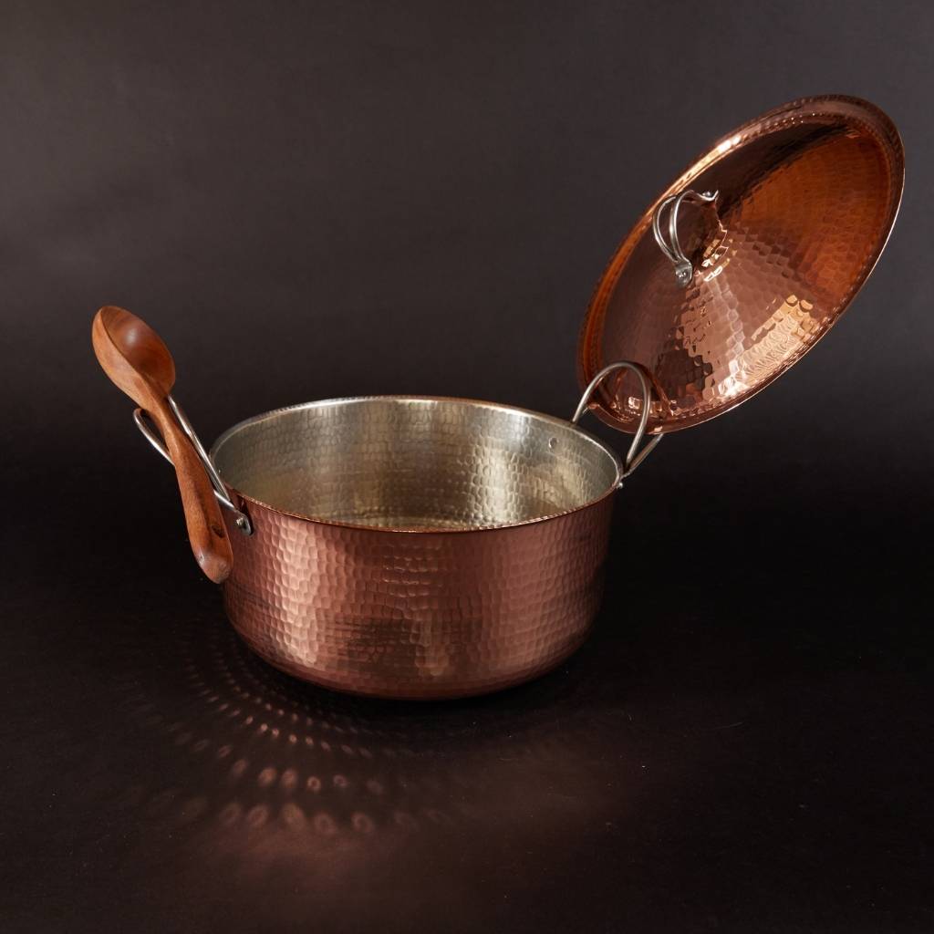 Copper pot with lid on a dark background