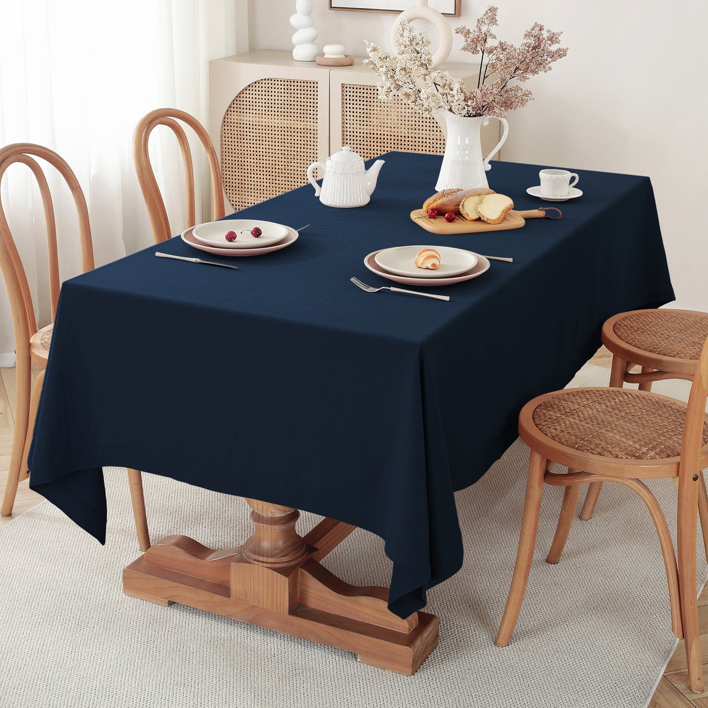Navy blue tablecloth on a wooden table with a breakfast setting and chairs in a room.