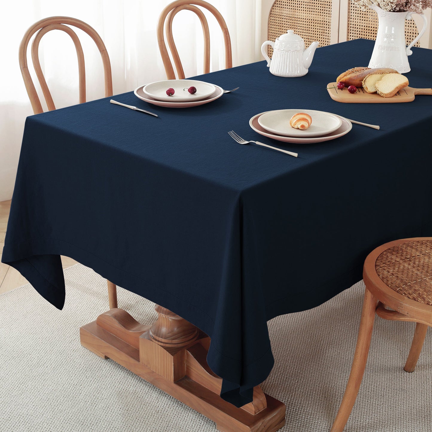 Navy blue tablecloth on a dining table with plates, cutlery, and a teapot.