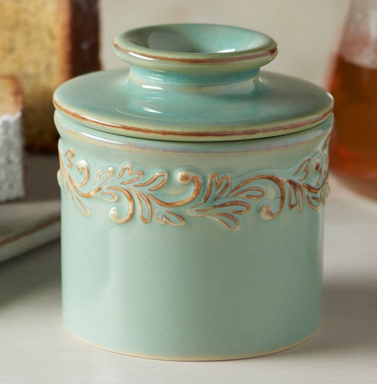 Decorative turquoise ceramic jar with gold embossed design on a neutral background