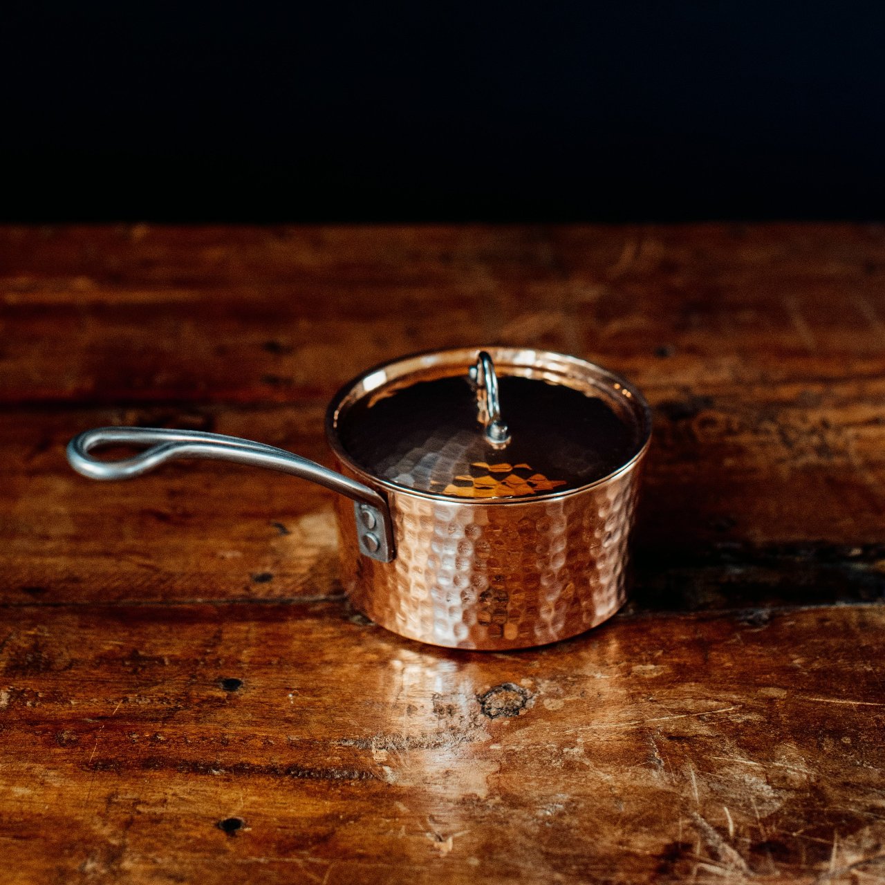 Copper saucepan butter pot with a lid on a wooden surface