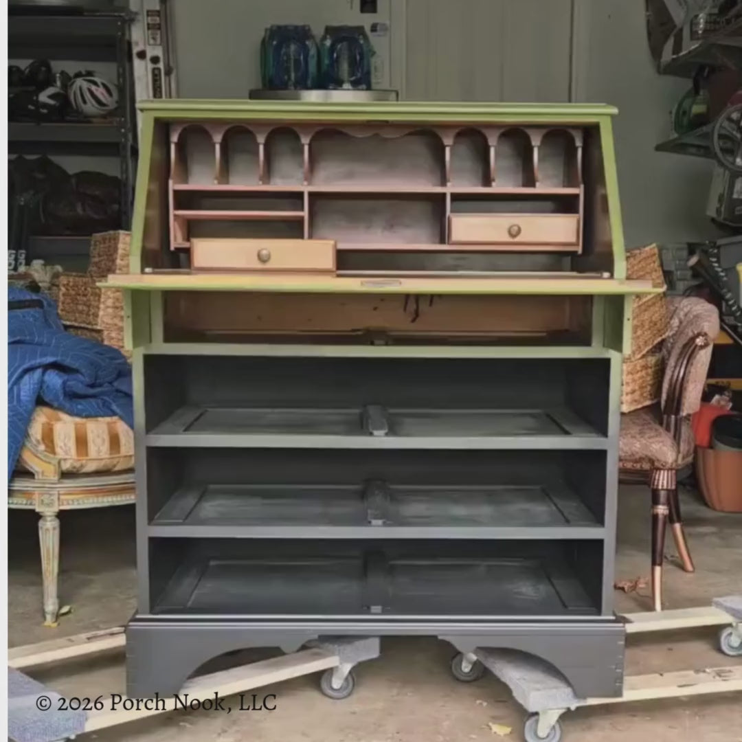 Video of vintage secretary desk with hand-painted green and black ombre finish, fold-down front panel with botanical frog decoupage, and rattan basket storage styled in a rustic interior