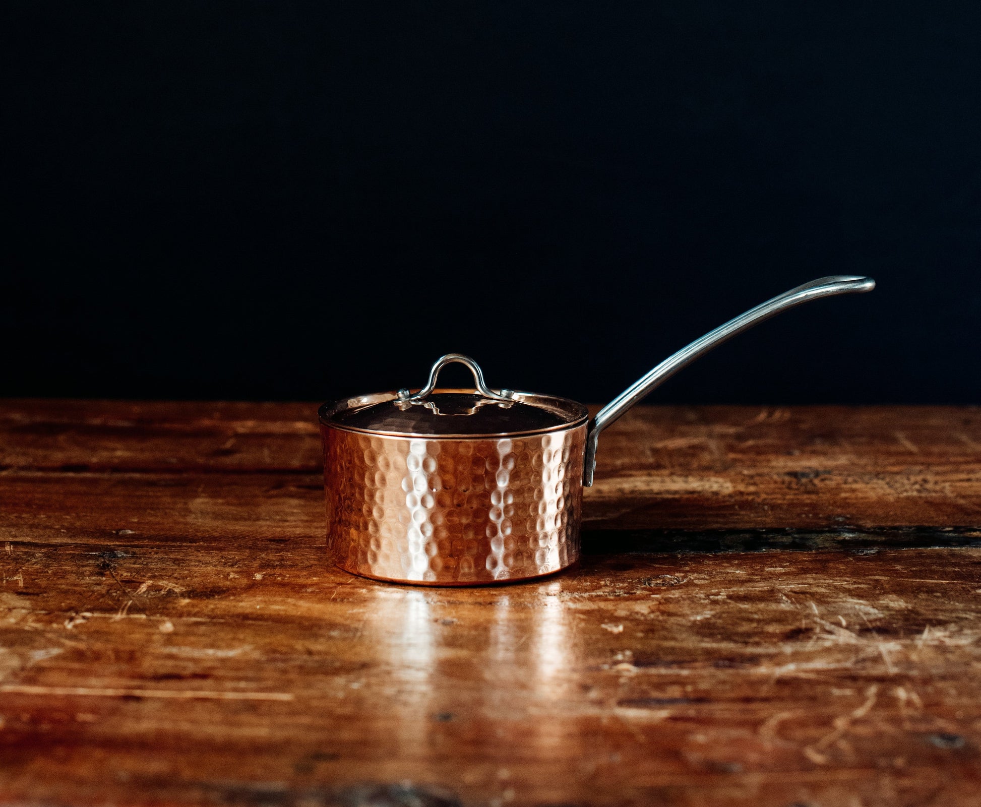 Copper saucepan butter pot with a lid on a wooden surface
