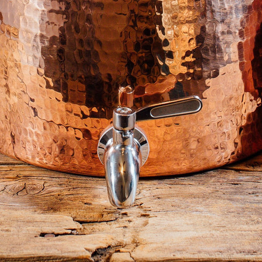 Copper pot with a spigot on a wooden surface